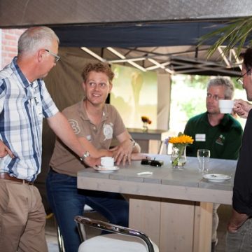 3 personen aan het praten met elkaar, met een kopje koffie